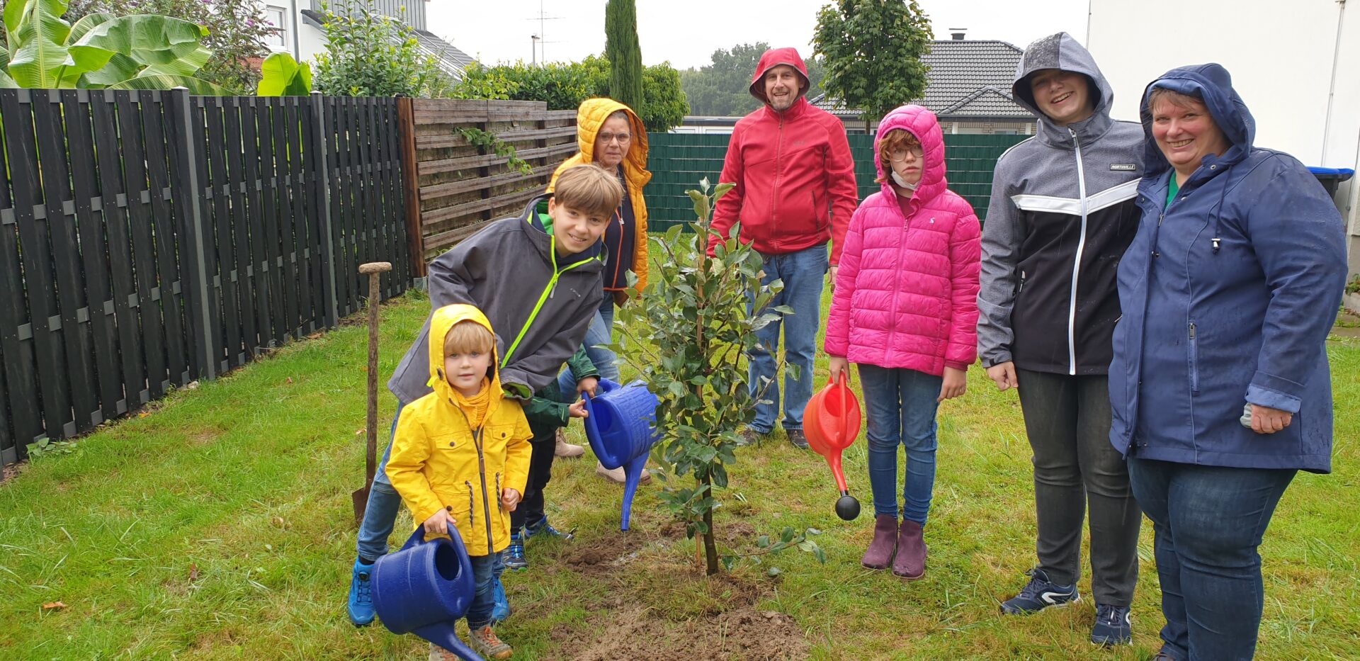 Evangelische Familien pflanzen Apfelbaum
